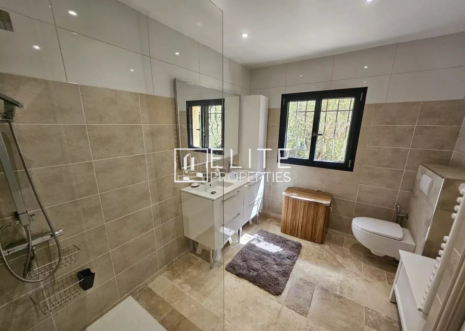Modern bathroom with shower, vanity unit and bright window.