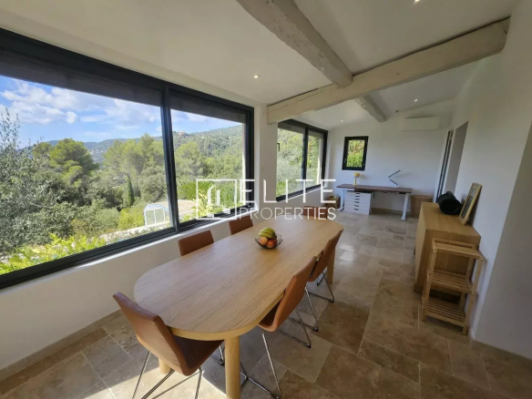 Interior of a bright dining room with a view of nature, wooden table and modern chairs.