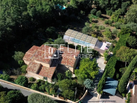 Aerial view of a detached house with swimming pool and garden in Cabris, surrounded by trees.