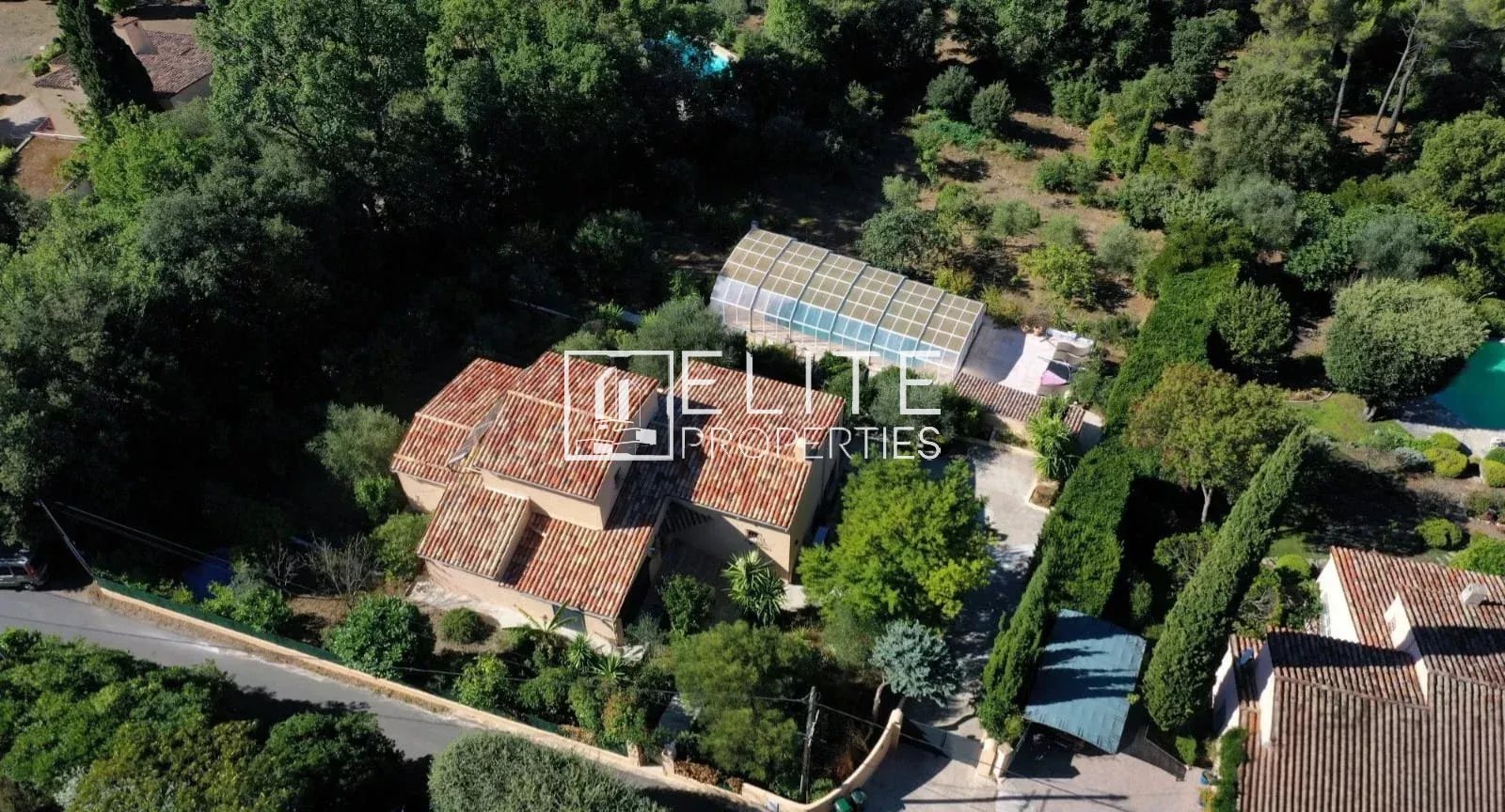 Aerial view of a detached house with swimming pool and garden in Cabris, surrounded by trees.