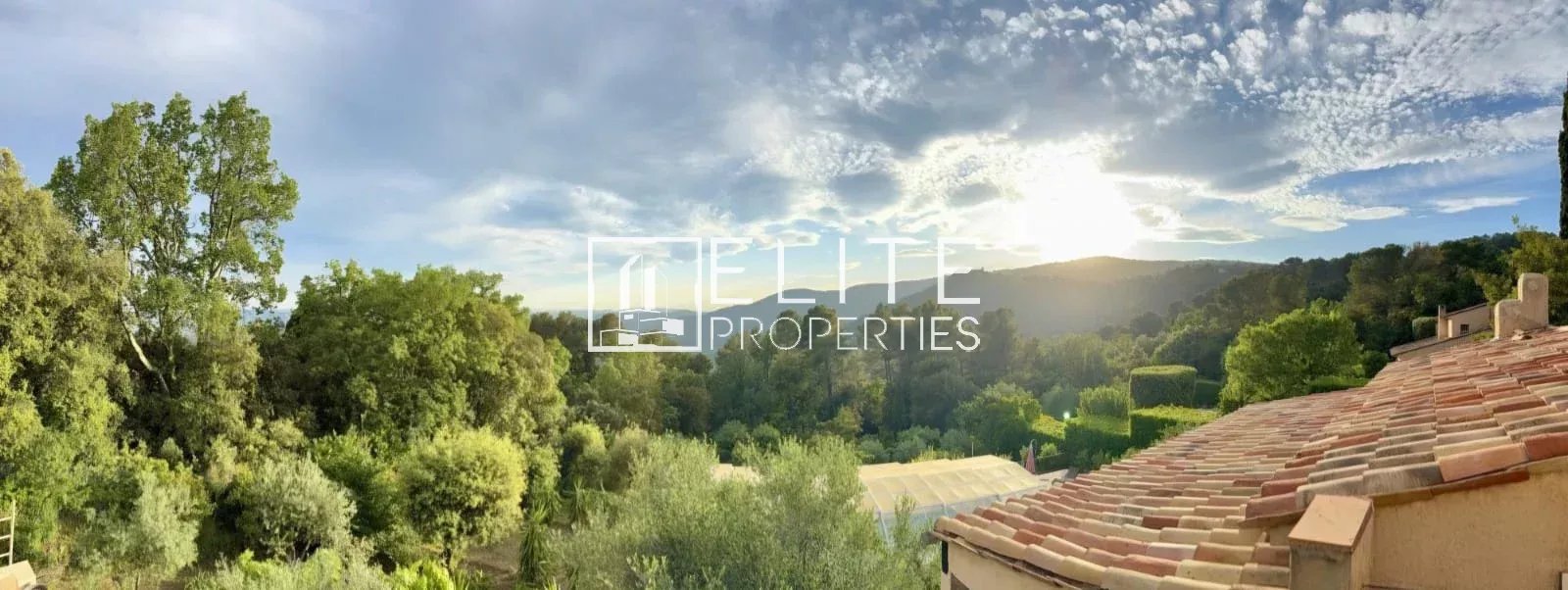 Panoramic view of nature and the village of Cabris, with a cloudy sky.