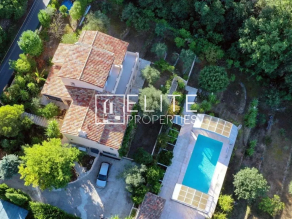 Aerial view of a house with swimming pool and garden in Cabris, surrounded by trees.