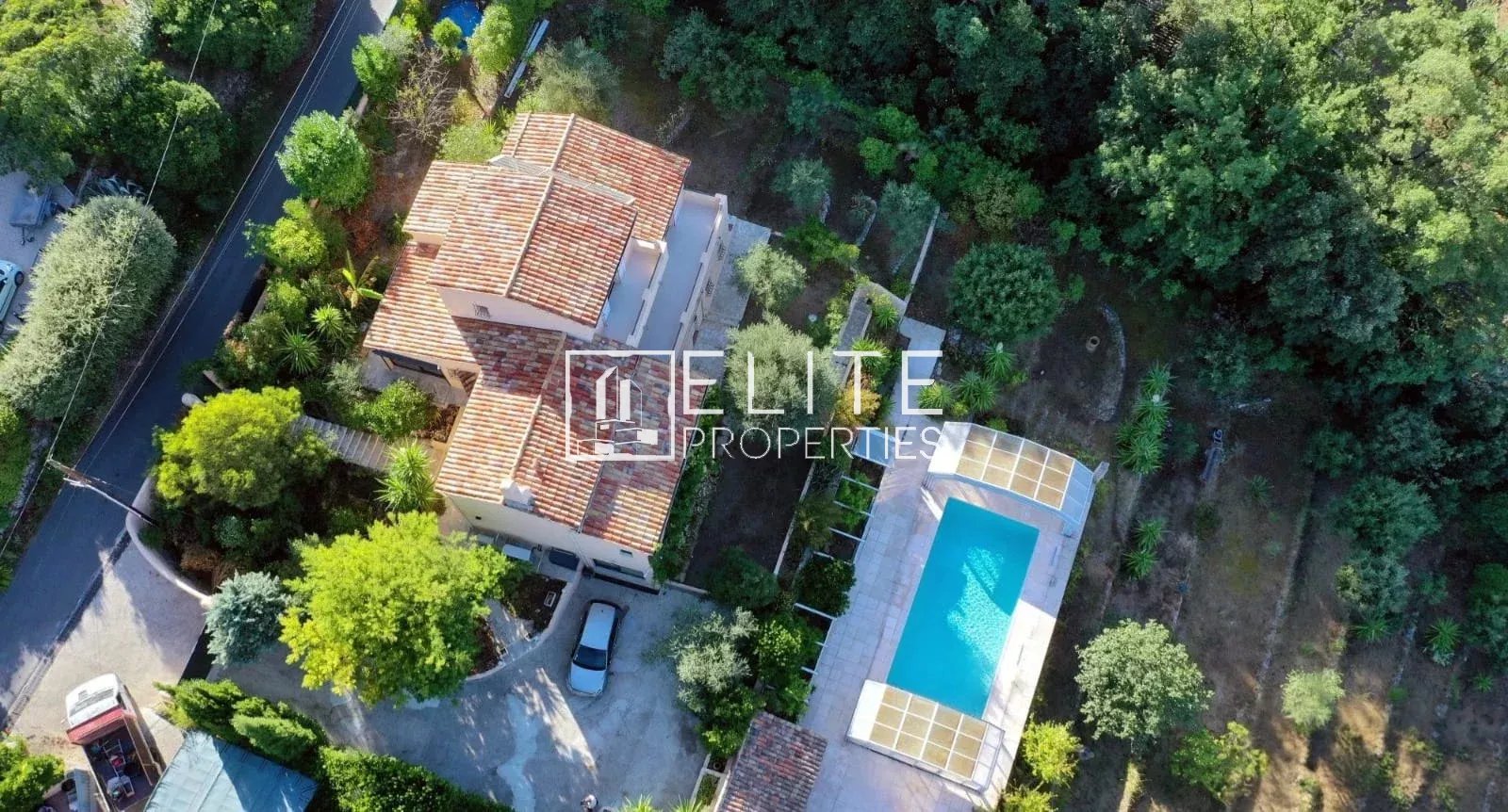 Aerial view of a house with swimming pool and garden in Cabris, surrounded by trees.