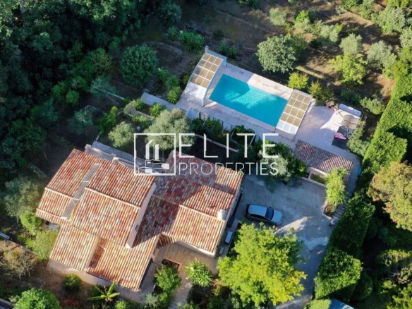 Aerial view of a house with swimming pool and garden in Cabris, surrounded by trees.