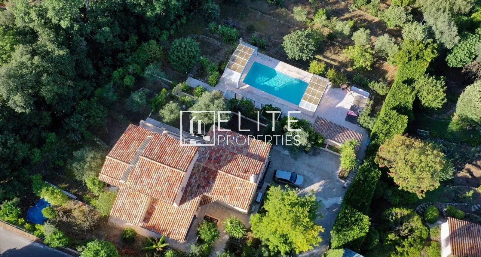 Aerial view of a house with swimming pool and garden in Cabris, surrounded by trees.