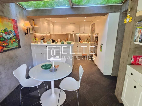 Modern kitchen with white table and chairs, opening onto a bright space.
