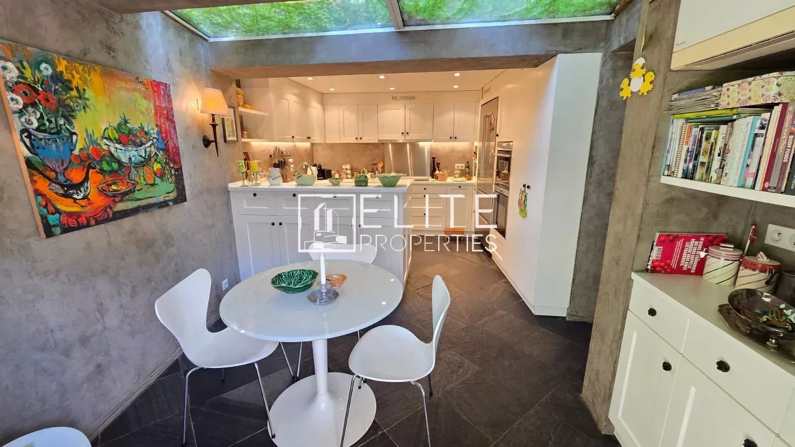Home cooking in Mouans-Sartoux Modern kitchen with white table and chairs, opening onto a bright space.
