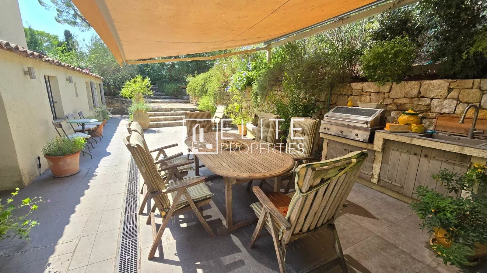 Terrace of the house in Mouans-Sartoux Outdoor terrace with wooden table and chairs, surrounded by greenery.