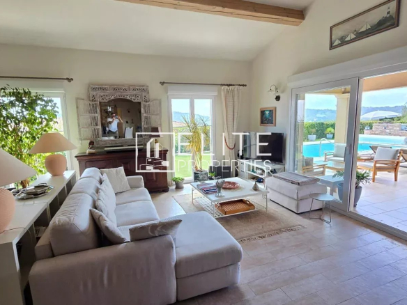 Intérieur d'une maison de plain-pied avec salon lumineux et accès à la piscine.