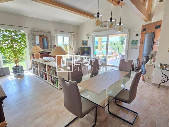 Intérieur d'une maison moderne avec séjour lumineux, salle à manger et accès à la piscine.