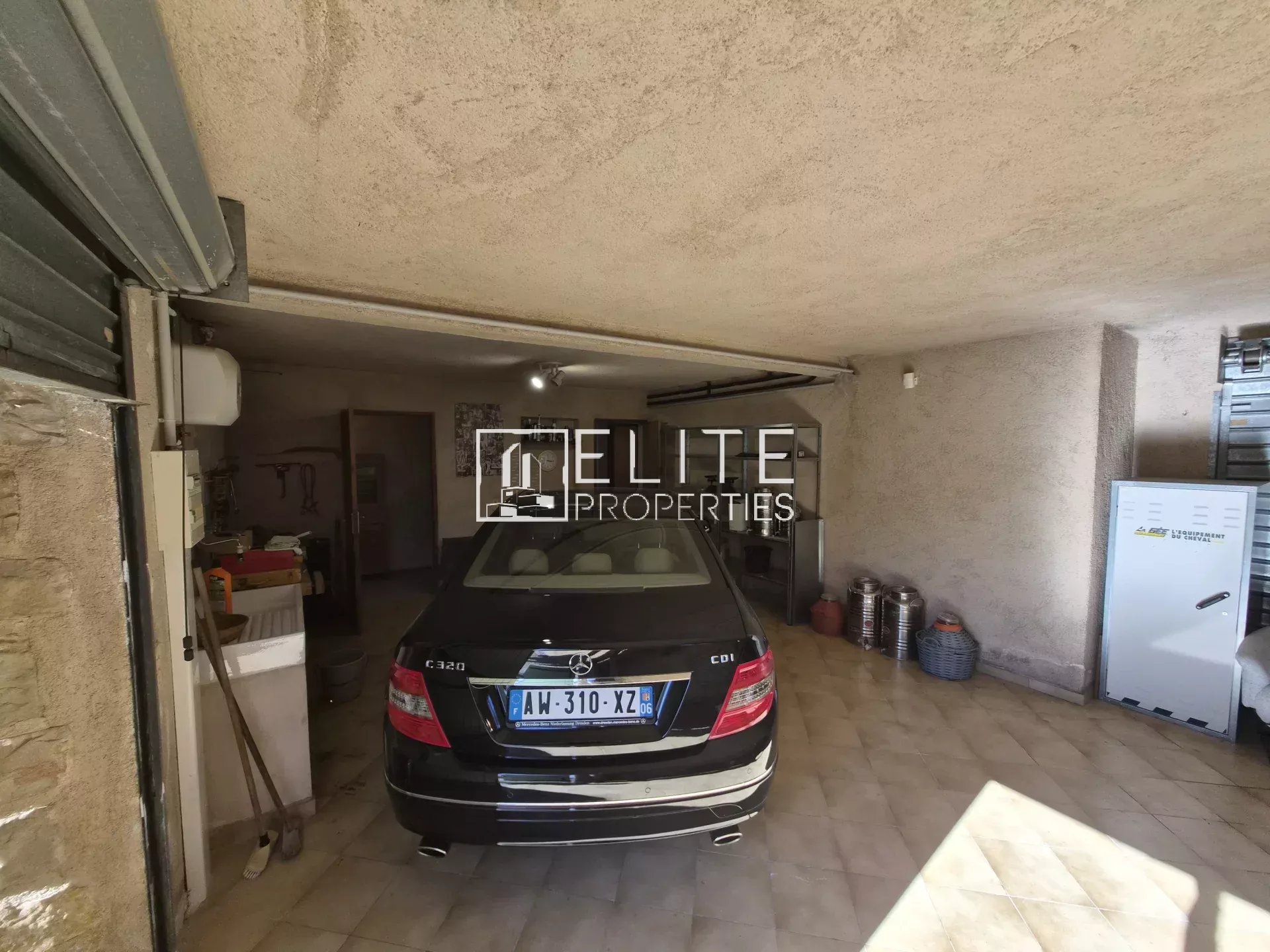 Intérieur d'un garage avec une voiture noire et des équipements visibles.