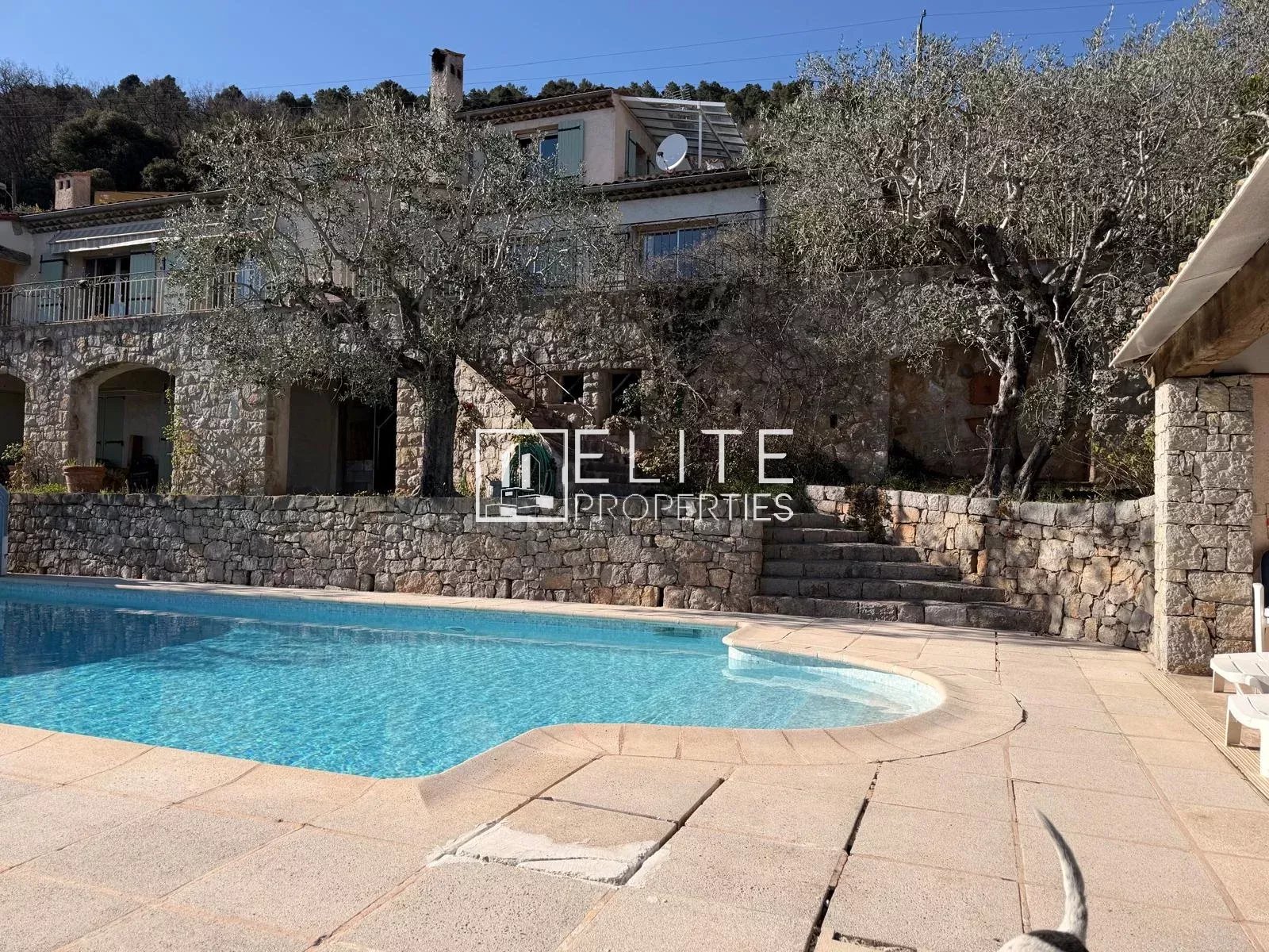 Villa avec piscine et vue panoramique à Spéracèdes, entourée d'arbres et de pierres.