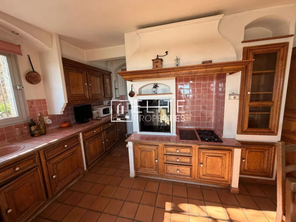Cuisine spacieuse avec meubles en bois et carrelage, située dans une villa à Spéracèdes.