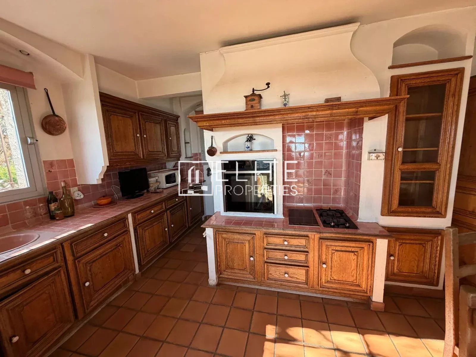 Cuisine spacieuse avec meubles en bois et carrelage, située dans une villa à Spéracèdes.