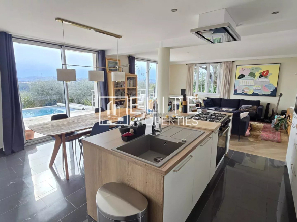 Intérieur d'une maison moderne avec cuisine ouverte et vue sur la piscine.