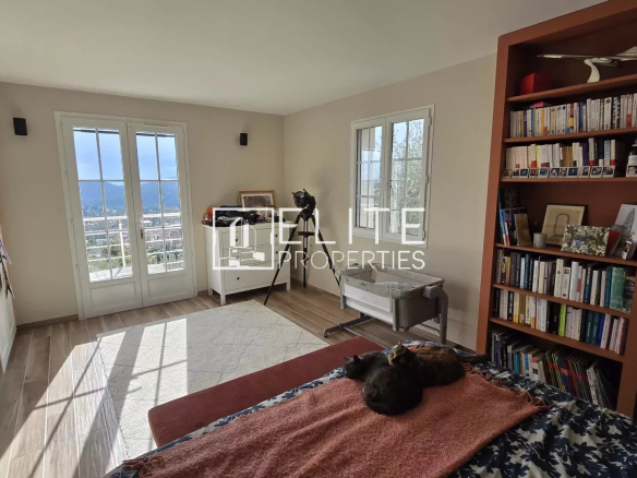 Chambre lumineuse avec vue, bibliothèque et lit, dans une maison à Cabris.