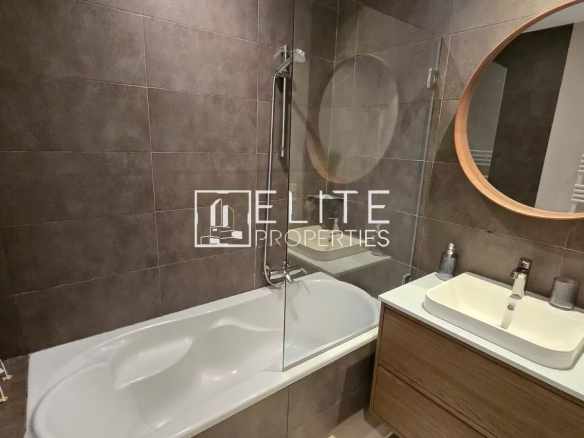 Salle de bain moderne avec baignoire, lavabo et miroir rond.