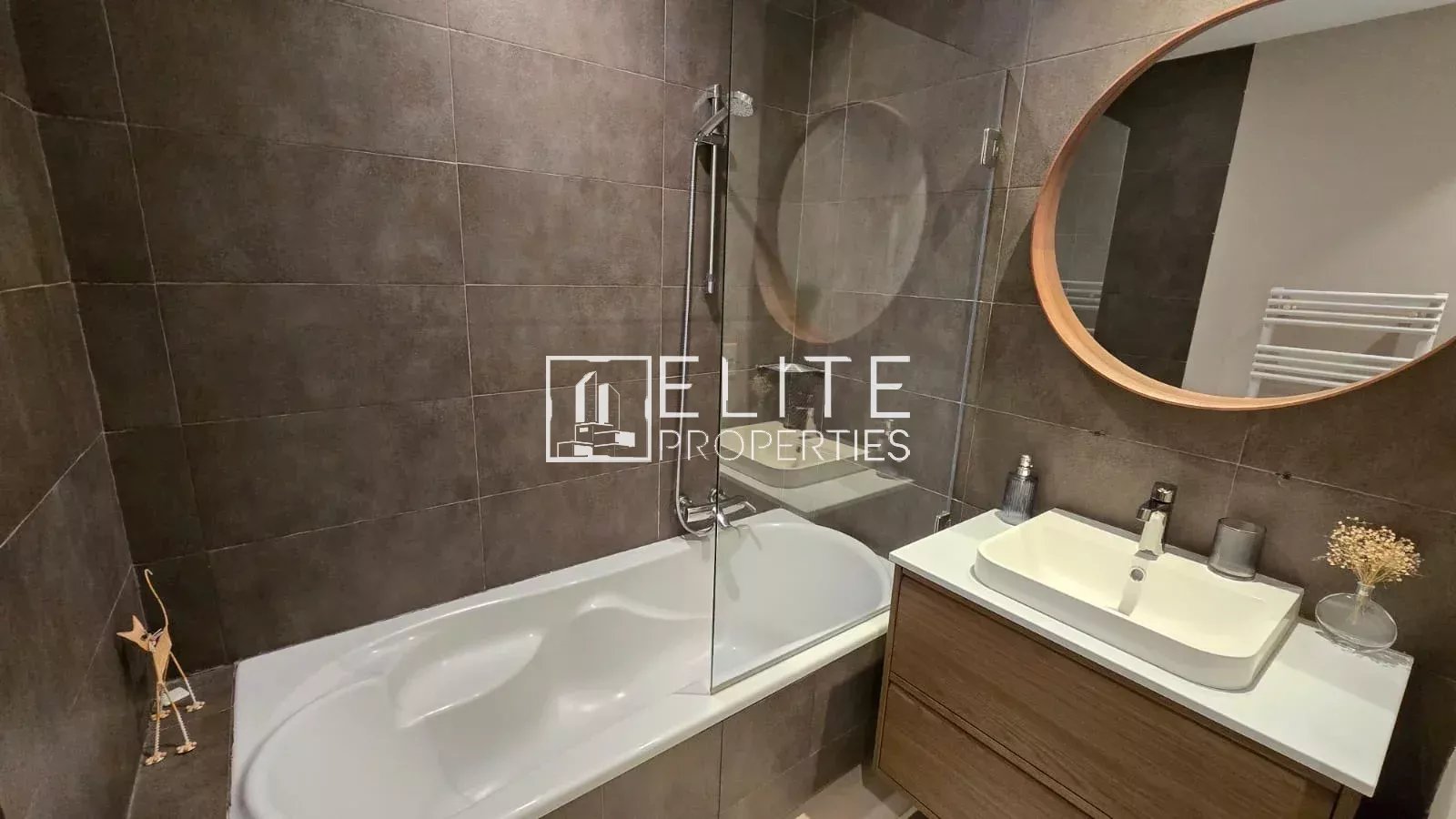Salle de bain moderne avec baignoire, lavabo et miroir rond.