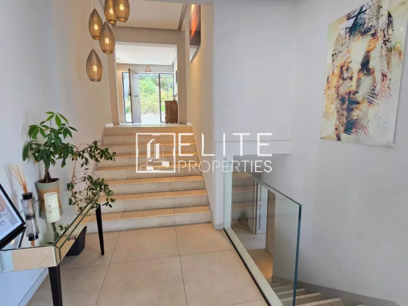 Intérieur d'une maison moderne avec un hall d'entrée lumineux et des escaliers.