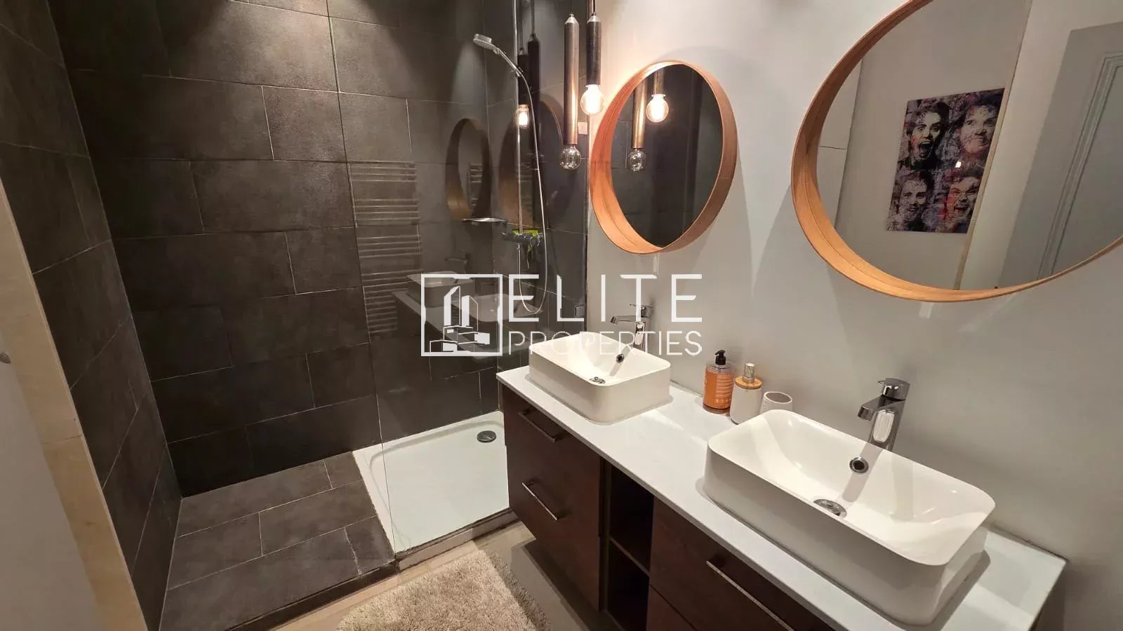 Salle de bain moderne avec douche, deux lavabos et miroirs ronds.