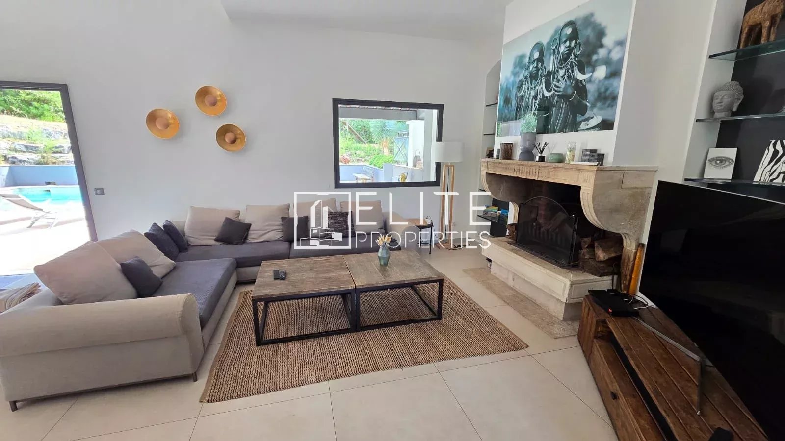 Intérieur d'une maison moderne avec salon, cheminée et accès à la piscine.