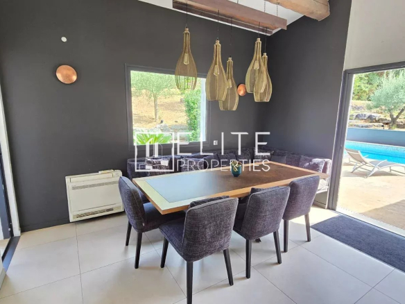 Salle à manger moderne avec table et chaises, vue sur piscine à Peymeinade.