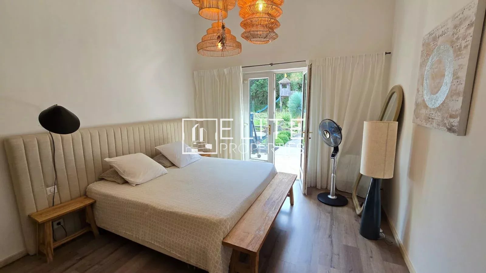 Chambre d'une maison à Peymeinade avec lit, fenêtres et décoration lumineuse.