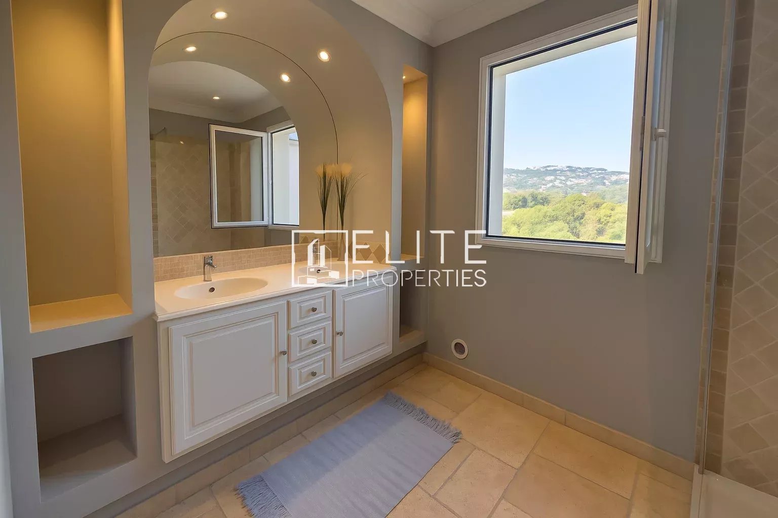 Modern bathroom with sink and window offering a view of nature.