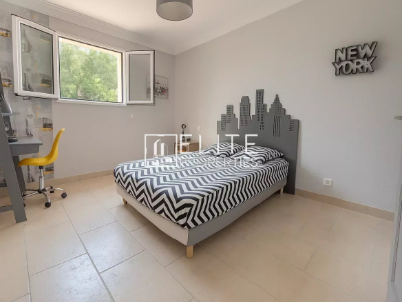Bedroom in a villa in Grasse with a striped bed and desk.