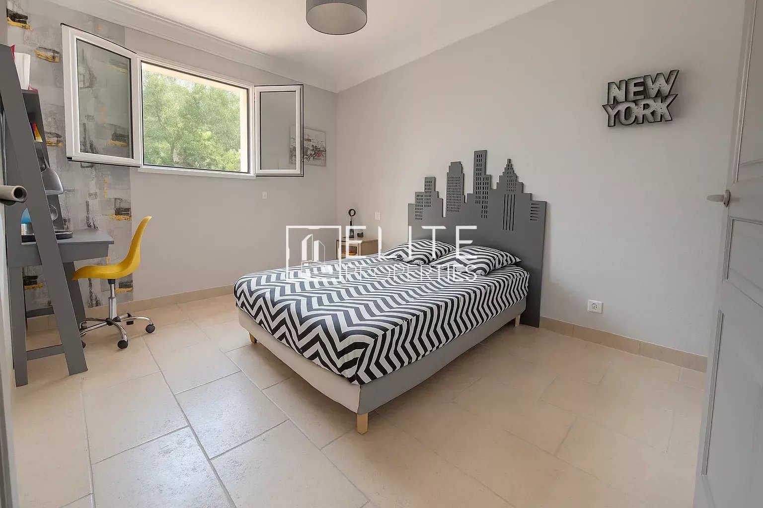 Bedroom in a villa in Grasse with a striped bed and desk.