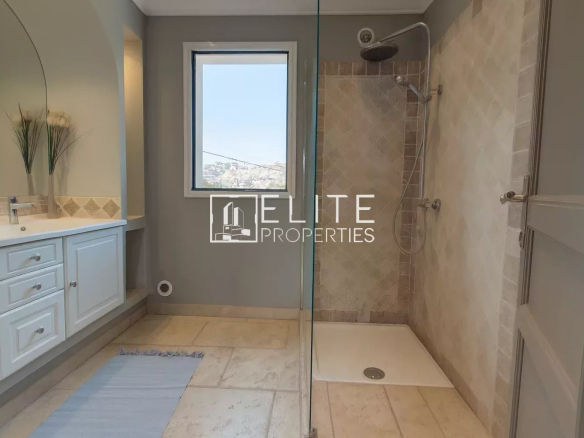 Modern bathroom with walk-in shower and sink, windows offering an unobstructed view.
