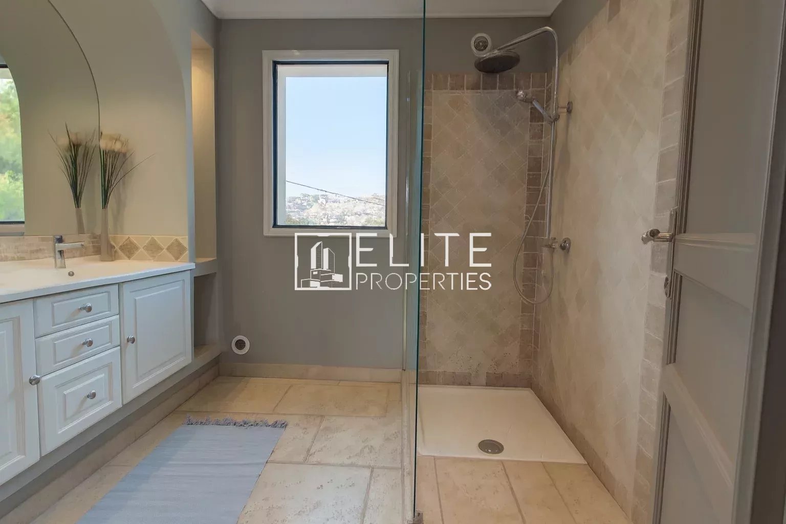 Modern bathroom with walk-in shower and sink, windows offering an unobstructed view.