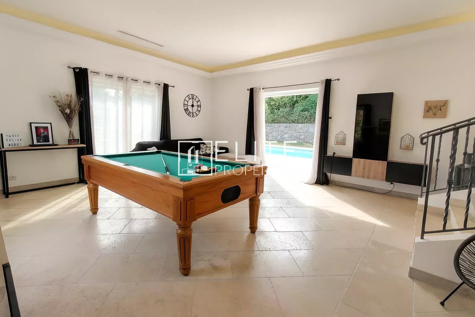 Interior of a villa with a pool table and access to the swimming pool.