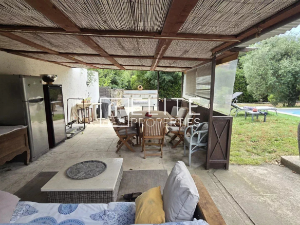 Terrasse couverte avec mobilier et piscine en arrière-plan dans une maison à Mougins.