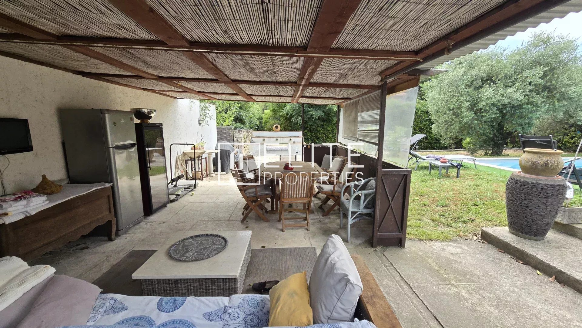 Terrasse couverte avec mobilier et piscine en arrière-plan dans une maison à Mougins.