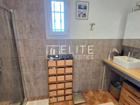Salle de bain moderne avec douche, lavabo et rangement en bois.