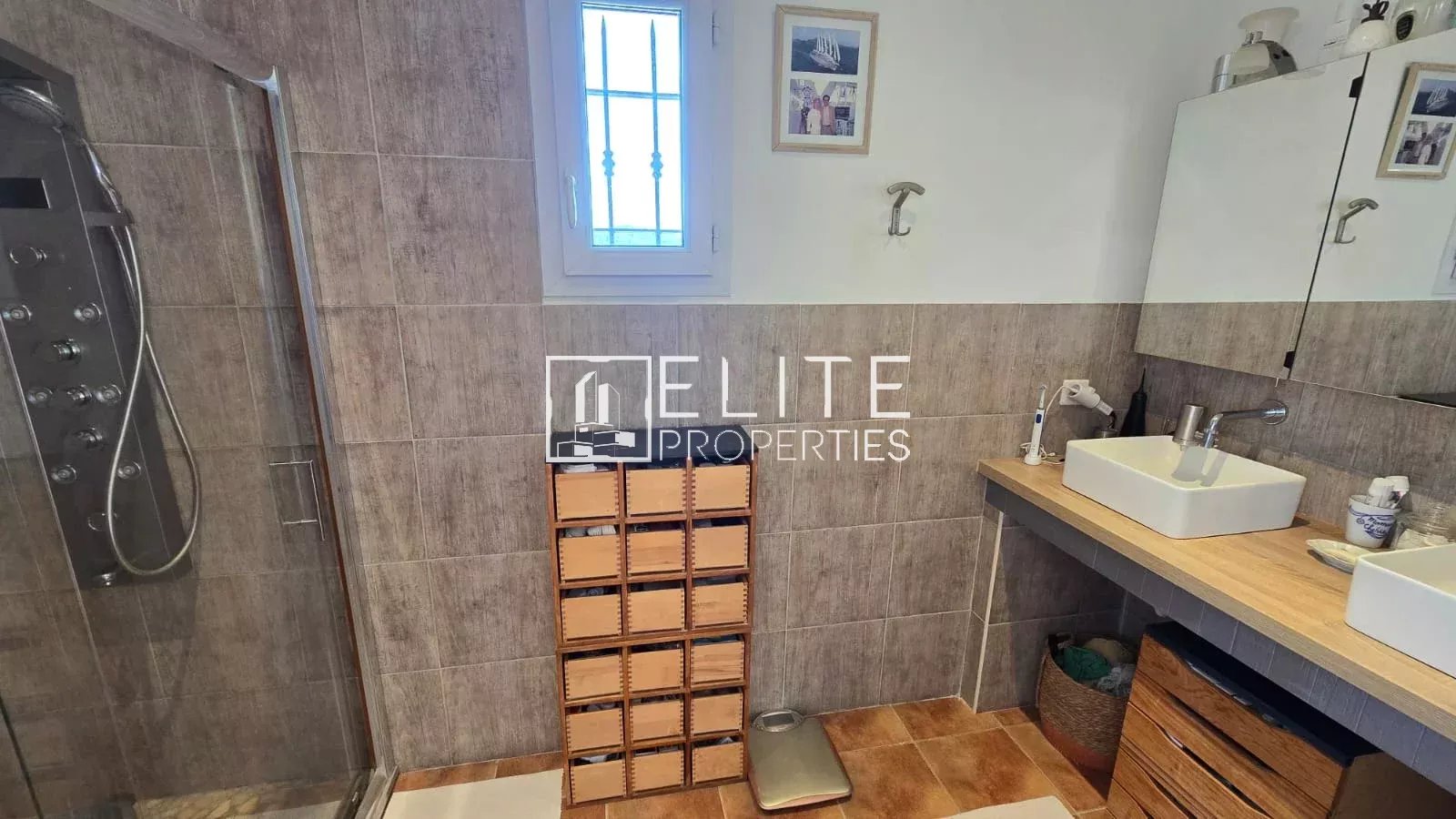 Salle de bain de maison à Tanneron Salle de bain moderne avec douche, lavabo et rangement en bois.