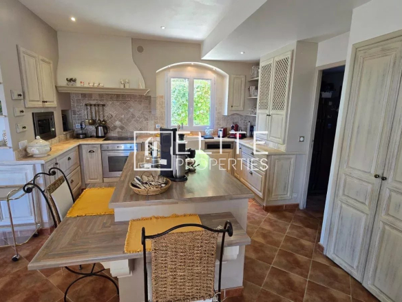 Intérieur d'une cuisine moderne avec salle à manger, meubles en bois, et vue sur l'extérieur.