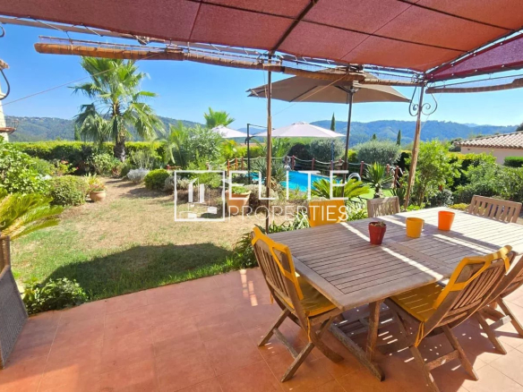Terrasse avec table et chaises, vue sur jardin et collines à Tanneron.
