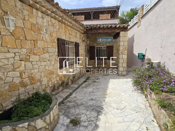 Entrée d'une maison en pierre avec un espace extérieur fleuri à Mandelieu-la-Napoule.