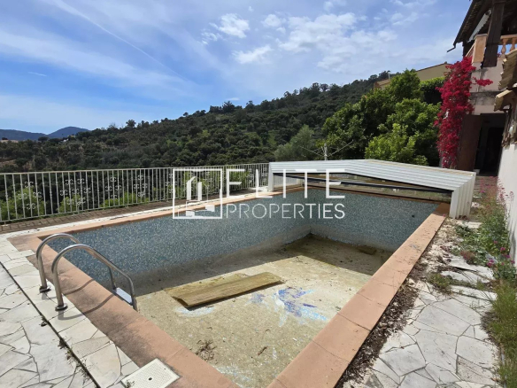 Piscine vide et espace extérieur d'une maison à Mandelieu-la-Napoule, avec vue sur la nature environnante.