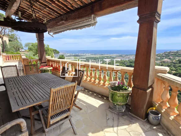 Terrasse d'une maison avec vue sur la mer et îles de Lérins, mobilier en bois, environnement calme.