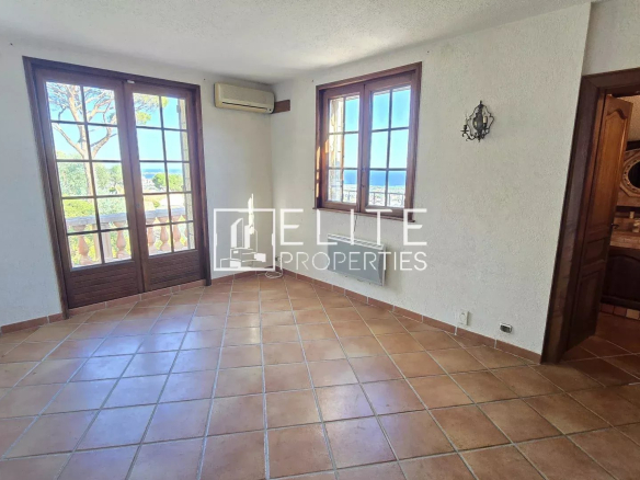 Interior of a house with windows overlooking the sea, tiled floor and light-colored walls.