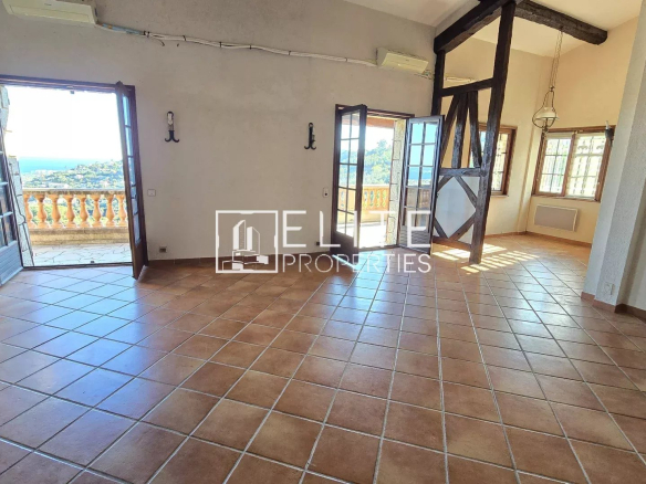Interior of a spacious house with tiled floors and large windows offering a view of the sea.