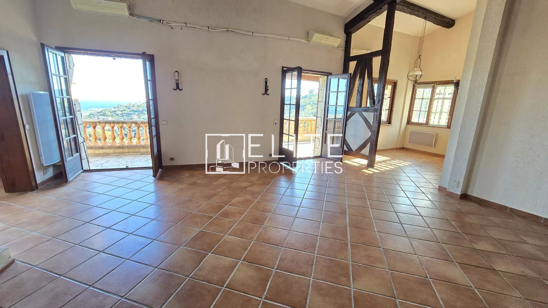 Interior of a house in Mandelieu-la-Napoule Interior of a spacious house with tiled floors and large windows offering a view of the sea.