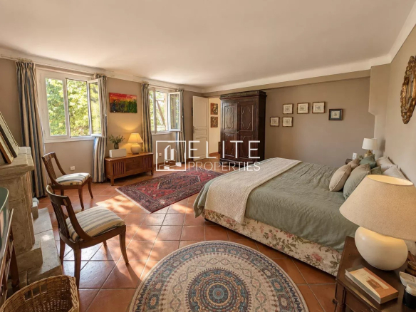Chambre spacieuse avec lit double, meubles en bois et tapis, lumière naturelle à Saint-Antoine, Grasse.