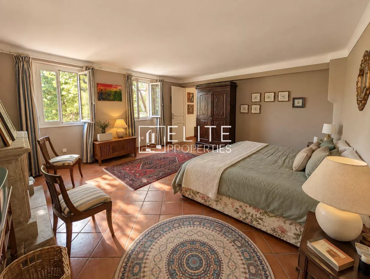 Chambre d’une bergerie à Saint-Antoine Chambre spacieuse avec lit double, meubles en bois et tapis, lumière naturelle à Saint-Antoine, Grasse.
