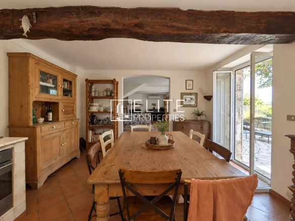 Intérieur d'une bergerie en pierres apparentes avec une grande table en bois et des chaises, à Grasse.