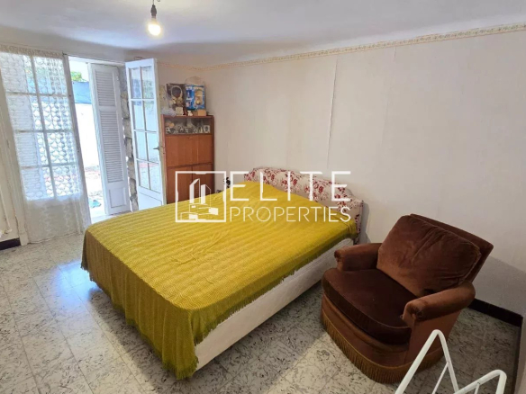 Chambre d'un appartement avec lit double et fauteuil dans une maison à Juan-les-Pins.