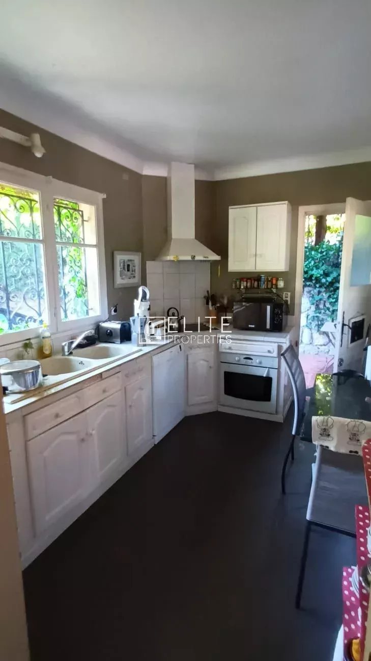 Cuisine d’une maison à rénover à Mougins Cuisine d'une maison de plain-pied à Mougins, avec meubles clairs et fenêtre donnant sur l'extérieur.